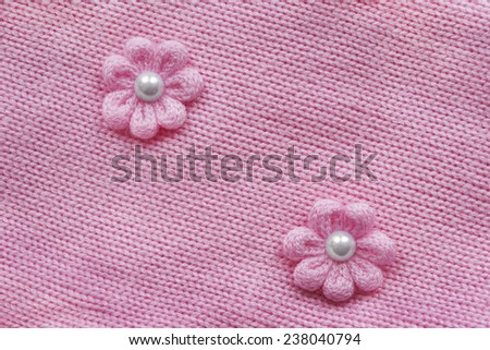Pink knitted cloth with two knitted flowers as a background