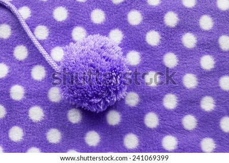Purple fleece cloth with one pompom as a background