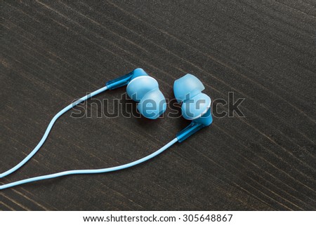 Blue wired earphones on wooden background
