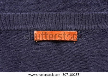 Blank orange label on violet knitwear as a background