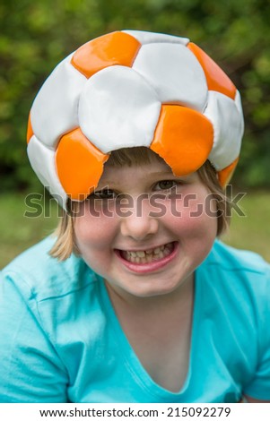 Young girl wearing orange white leather football on head