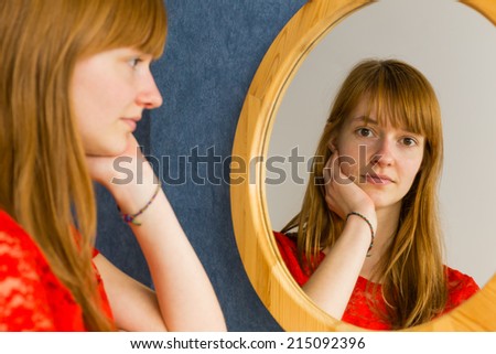 Redhead teenage girl looking in mirror