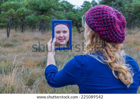Girl looking in mirror with forest nature background