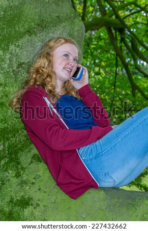Girl calling with mobile phone in green tree
