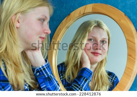 Portrait of blonde girl looking at reflection in mirror