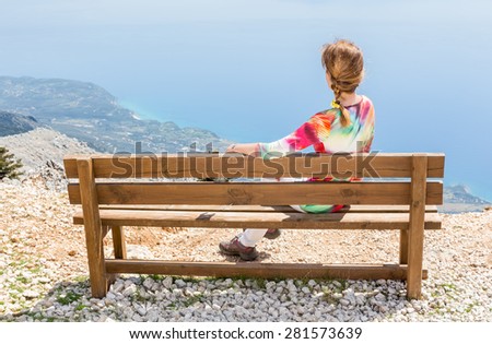 Woman sitting on bench on top of mountain enjoying the view
