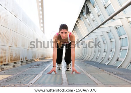 Beautiful young woman getting ready to run on a modern bridge