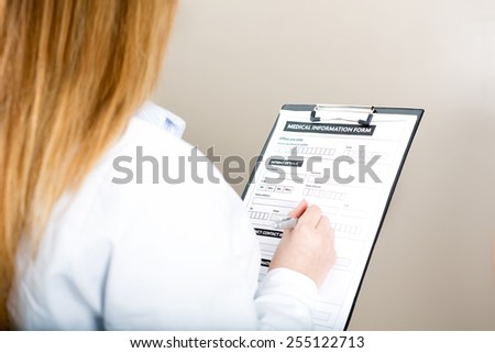 Female doctor compiling medical information form in medical center.