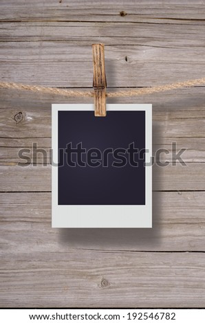 Blank instant photo hanging on the clothesline. On old wood background.