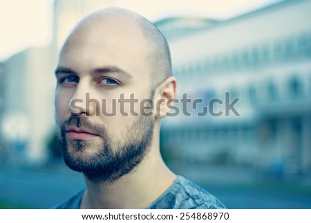 Shot of a handsome young man with beard and green eyes/Attractive man in urban city background