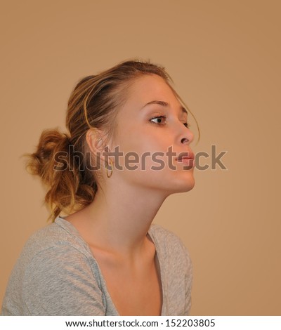 Close-up face portrait of the young woman looking at the side on a neutral background