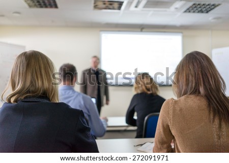 people sitting rear at the desks in the education class and the lecturer near the white desk