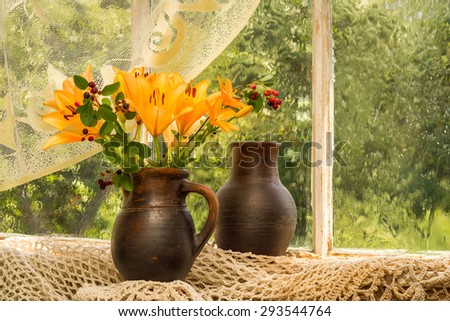 Asiatic Hybrids orange lilies bouquet on a window sill in a sunny rainy day. Good mood emotions of orange color.