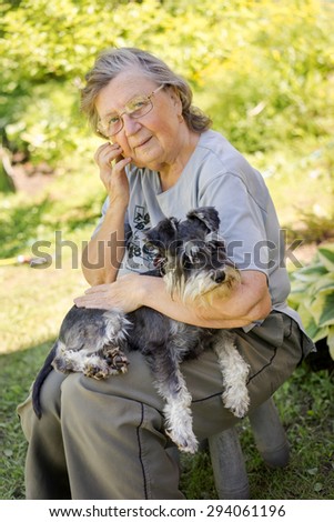 senior 70s woman holding her black and silver mini schnauzer dog sitting outdoor