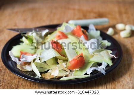 heap of rotten food waste closeup on a black plate