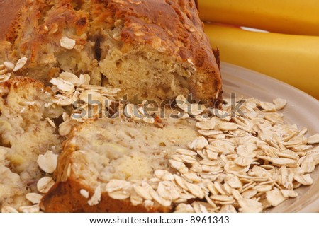 Closeup of banana nut oat bread with bananas in the background