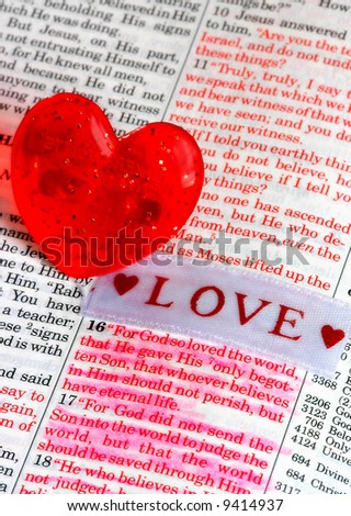 Plastic heart sitting next to words from John 3:16 in the Bible