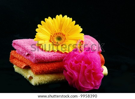 Bright colored wash cloths with flower and bath pouffe on a black background