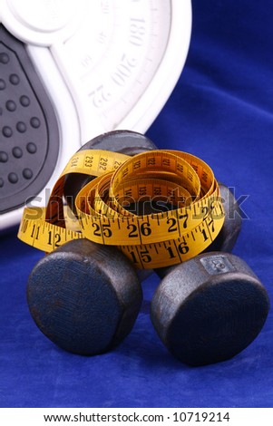 dumbbells, tape measure and scale on a blue background