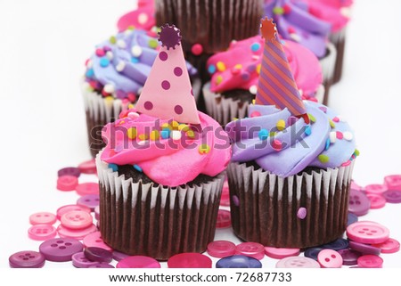 mini cupcakes with pink and purple icing and multi-colored sprinkles with buttons on an isolated white background