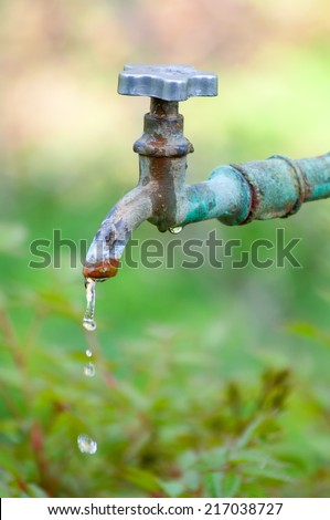 Old tap with leaking water. Closeup with shallow DOF.