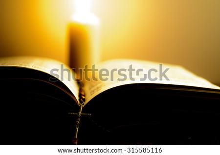 Burning candle with bright flame near the opened book with rosary. Shallow DOF. Imagine de stoc © 