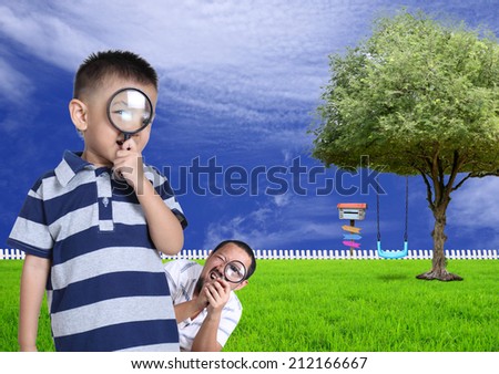 Little boy and his funny father with magnifying glass in the garden.