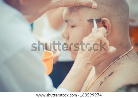 BANGKOK, THAILAND - MAY 20 : Thai man gets his head shaved by a monk during a Buddhist ordination ceremony on May 20, 2013 in Bangkok, Thailand.