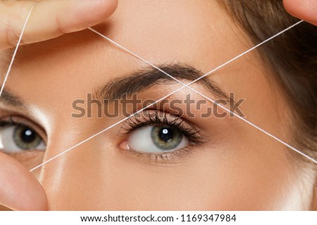 Close-up of female eye with a thread. Eyebrow threading - epilation procedure for brow shape correction Stockfoto © 