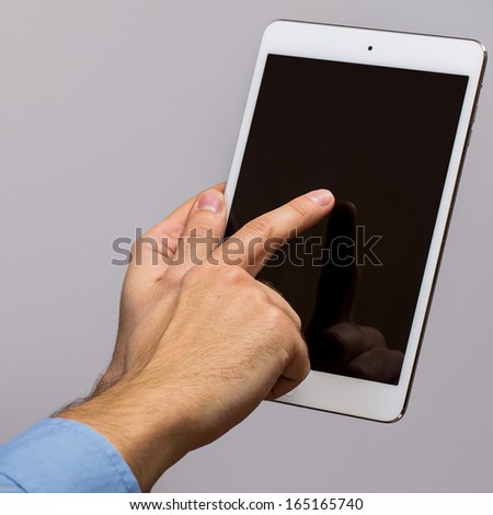White tablet pc in hands over gray background