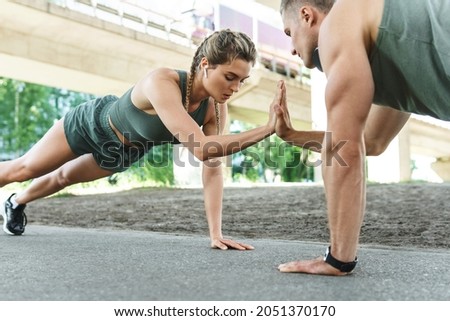 Athletic couple and fitness training outdoors. Man and woman doing push-ups exercise for chest and triceps muscles during street workout  Foto stock © 