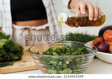 Closeup of female hand adding extra virgin olive oil to vegetarian salad Stock foto © 