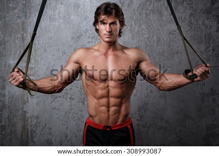 Muscular man during workout with suspension straps