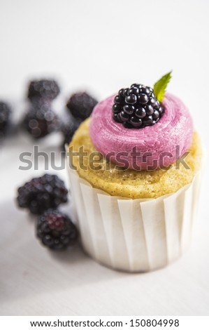 Blackberry Buttercream Vanilla Cupcakes in White Cupcake Wrappers on a White Wood Natural Background
