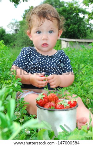In the summer, the garden beds near the little girl is sitting, and near it is a full circle of strawberries