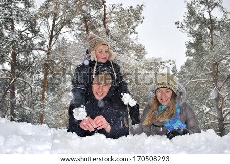 Winter fun. Dad mom and son lie on the snow in the woods near pines and laugh.