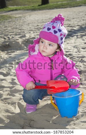 In the spring of  little girl playing on the playground, she digs a shovel sand.