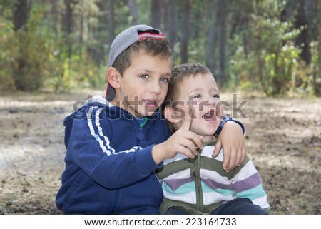 Brother in a pine forest, hugged his little sister and something she says she was surprised and laughing.