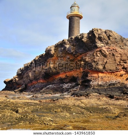 Reef and old stone lighthouse on the cliffs in tip of Jandia, coast of fuerteventura, Canary islands, Spain