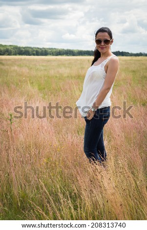 Girl in sunglasses in the field. Young girl standing in a field, girl, grass, nature, sunglasses. - The concept of enjoy nature. Application for an article about nature and healthy lifestyle.