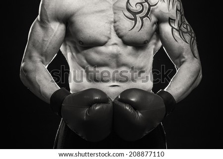 A man with a tattoo in red boxing gloves. Man boxing on black background. Boxer, boxing, tattoo, strength, punch, punching bag. - The concept of a healthy lifestyle.The idea for the film about boxing.