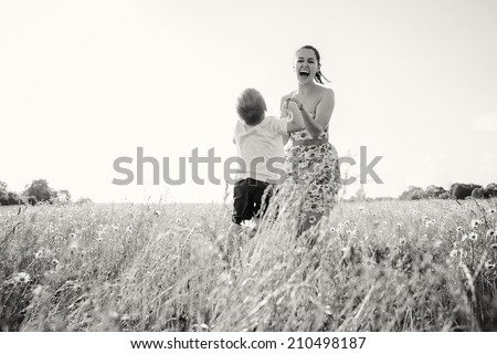 Mom and son in the summer field. Mother playing with her son in the catch-up. Mother and son having a great weekend. Games, field, family weekend - family-friendly concept. Article about the family.