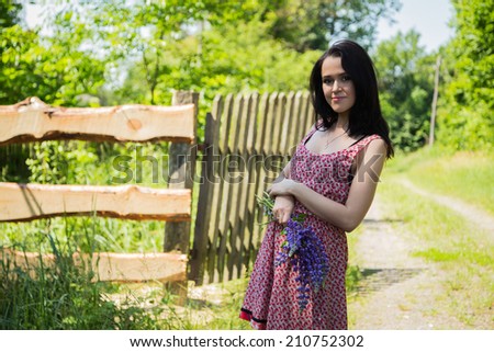 Girl with blue flowers. The girl stands near a wooden fence and smelling flowers. Flowers, girl, holiday, vacation holiday. The concept of happiness and carefree. Idea of ??an article about weekend.