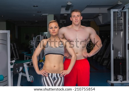 Man and woman in the gym. Fitness, sport, training, gym and lifestyle concept - two smiling people standing in the gym. The idea of article about sport and fitness.