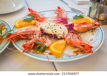 Dish with shrimp on the table in the restaurant. Shrimp are beautifully laid out on a platter with lemon. Seafood restaurant, shrimp, very tasty. Concept of healthy food. Article about cooking seafood