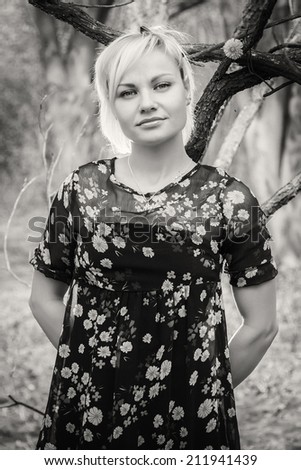 Black and white. Beautiful blonde in a garden. Girl enjoying nature. Garden, beauty, trees, - concept of enjoying nature. Idea of  the article about the garden and nature.