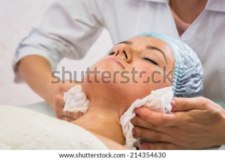 Girl with a beautician at spa salon. Beautician performs cosmetic procedures.applying cosmetic cream by brush. Cosmetology, facial, beauty - The concept of facial skin care. Article about cosmetology.
