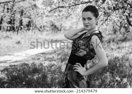 Black and white. Beautiful brunette in a lush spring garden. Girl enjoying flowering trees. Garden, beauty, flowers, - concept of enjoying nature. Idea of ??the article about the garden and nature.