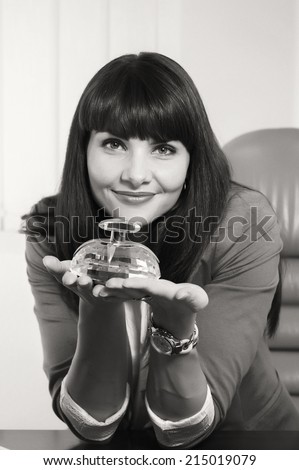 Modern business woman employee of the perfume company. Business lady sitting at a desk. Woman holding a bottle of perfume, offers its customers. Cosmetics, perfumes, sales concept of women\'s business.
