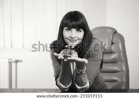Modern business woman employee of the perfume company. Business lady sitting at a desk. Woman holding a bottle of perfume, offers its customers. Cosmetics, perfumes, sales concept of women\'s business.